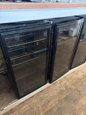 two glass door refrigerators sitting on top of a hard wood floor