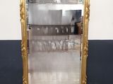 une photo représentant un grand miroir encadré d'or dans une pièce
