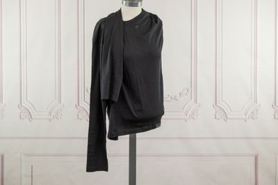 une chemise noire posée sur un mannequin devant un mur blanc
