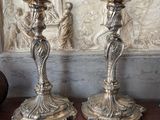 two silver candles sitting on a table next to a vase