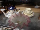 une statue représentant une femme tenant une tasse et une soucoupe posées sur une table