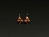 une paire de boucles d'oreilles ornées de perles, posée sur une surface noire