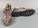 pair of brown hiking boots with fur lined soles on grey surface