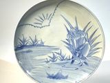 une assiette bleue et blanche ornée d'un oiseau et de fleurs