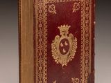 an old red book with gold trim and a crown on the cover