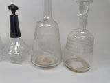 three glass bottles and a small glass bottle on the table