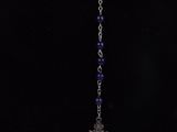 a necklace with a cross and beads on a black background