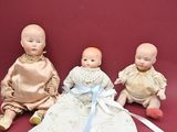 three dolls sitting next to each other on a red surface
