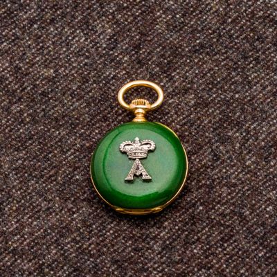 une photo d'une montre de poche verte et dorée