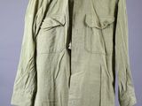 an army green jacket on a mannequin stand against a gray background