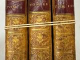 trois vieux livres posés l'un sur l'autre sur une table