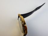 gros plan d'une montre sur une surface blanche avec un bracelet noir