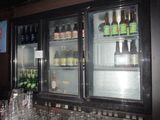 many bottles of beer in the fridge behind the glasses