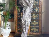 a statue of a woman holding a vase on top of a cabinet