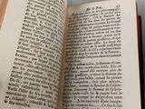 someone is holding a book open on a table with a pen in it