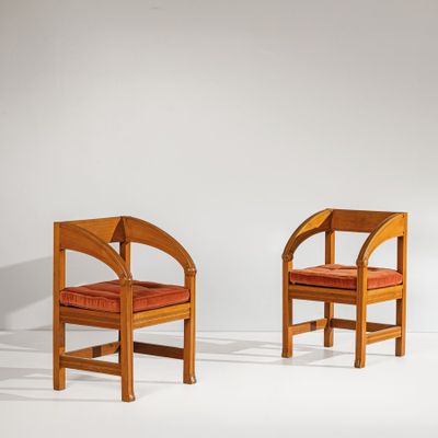 Deux chaises en bois avec des coussins rouges sont adossées à un mur blanc.