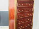 an antique wooden chest of drawers with gold trimmings