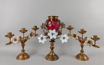 trois bougeoirs en or ornés de fleurs et un vase rouge