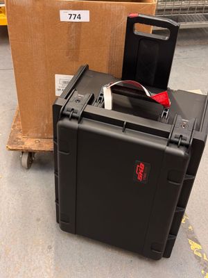 une valise noire posée par terre à côté d'une boîte