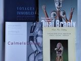 trois livres sont posés sur un lit recouvert d'un drap blanc