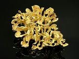 Broche en forme de fleur plaquée or jaune sur fond noir avec reflets