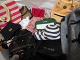 a pile of purses and handbags sitting on a bed
