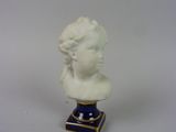 un buste de femme blanc posé sur un socle bleu et or