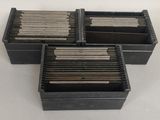 trois boîtes noires contenant des tiges métalliques, posées sur une table