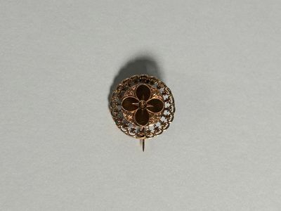 une image représentant une broche en or posée sur une surface blanche