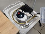 a white toilet with a black tank and a yellow hose