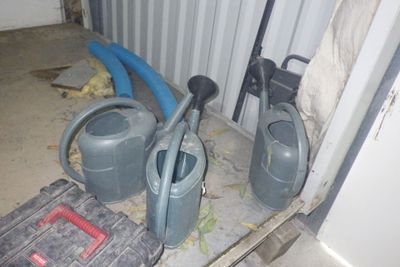deux arrosoirs et un sac à outils posés par terre