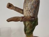 une vieille figurine en bois représentant un singe sur une souche d'arbre