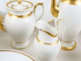 a white and gold tea set on a white table