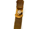 une montre en or entourée d'une chaîne sur une surface blanche