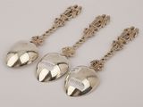 three silver spoons with hearts on them sitting on top of a table