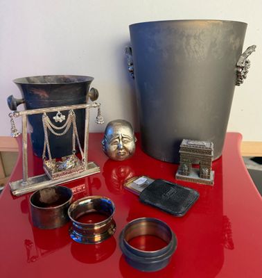 une table rouge sur laquelle sont posés des objets en argent et un seau en métal