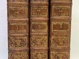 trois vieux livres sont empilés sur une surface blanche