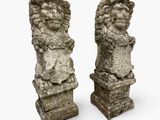 two stone statues of lions on pedestals on a white background
