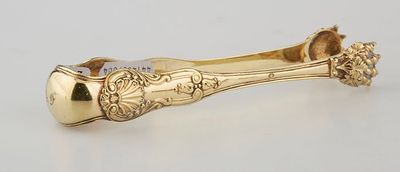 a gold plated spoon and spoon rest on a white surface