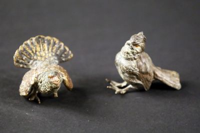 paire de figurines d'oiseaux de couleur argentée posées sur un fond noir