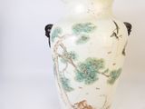 un vase blanc avec un tableau posé sur une table