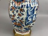 a blue and white vase with a gold handle on a table