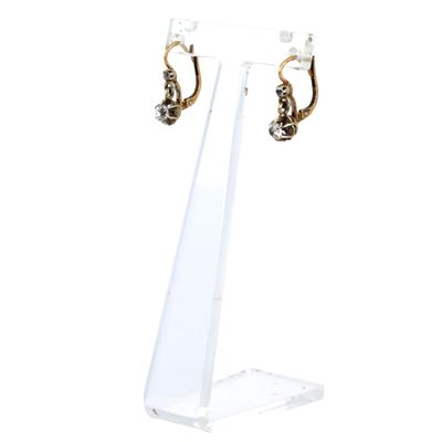 un gros plan d'une paire de boucles d'oreilles posées sur un présentoir transparent