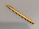 une image représentant un stylo doré posé sur une surface blanche