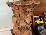un vase en bois contenant des fleurs, posé sur une étagère