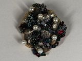 a picture of a brooch with pearls and beads on it