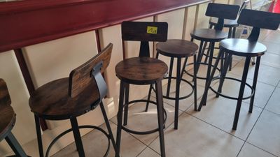 four wooden stools sitting in front of a bar