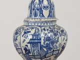 a blue and white vase with a bird on top of it