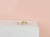 une bague en or sertie d'un diamant, posée sur un bloc de marbre blanc