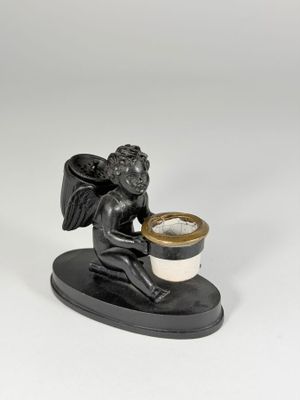 statue of a cupid holding a cup of coffee on a stand
